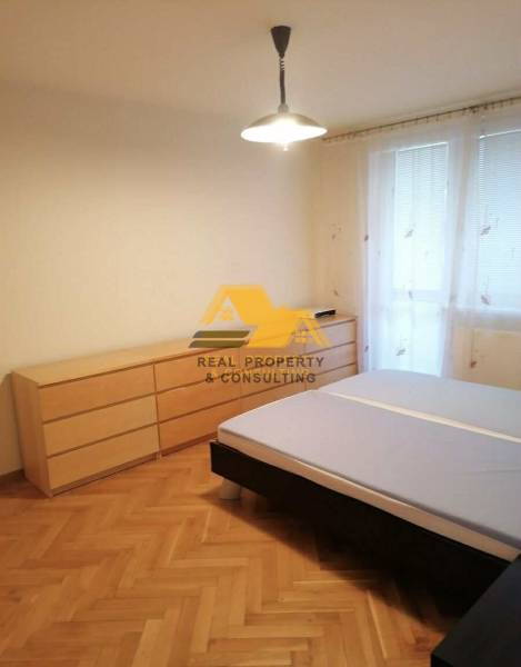 Bedroom in a 3-room apartment with a bed and a dresser on a floor with wood decor.