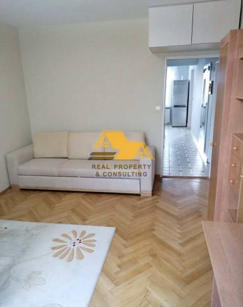 Living room in a three-room apartment with a wooden decor floor and a light sofa.