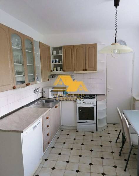 A kitchen with white cabinets, a gas stove, and a tiled floor in a three-room apartment.