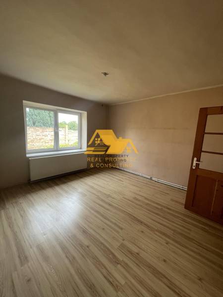 A room with a large window and a wooden decor floor in a family house.