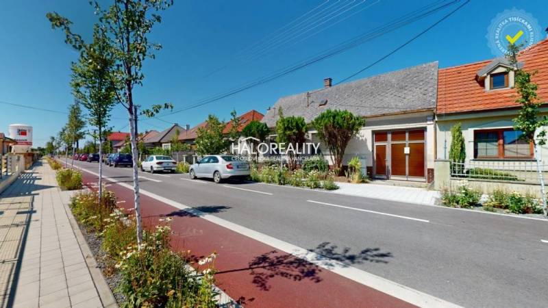 A street with family houses in Malacky, cars parked by the road, a cycling path.