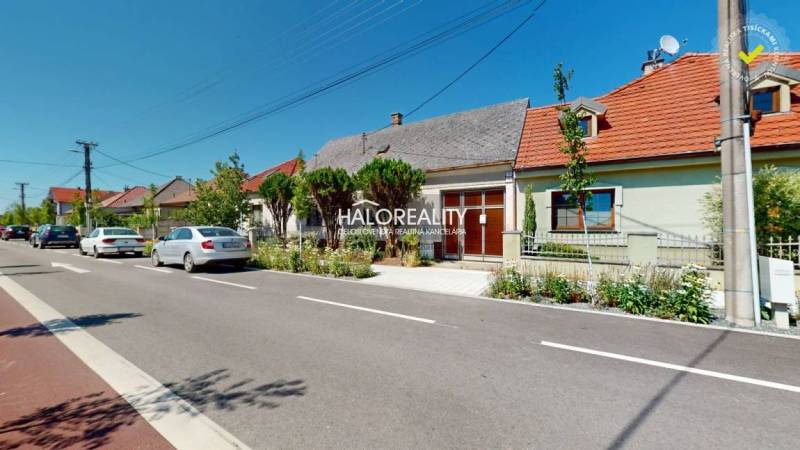 A family house in Malacky with a garden, cars parked on the street in front of the house.