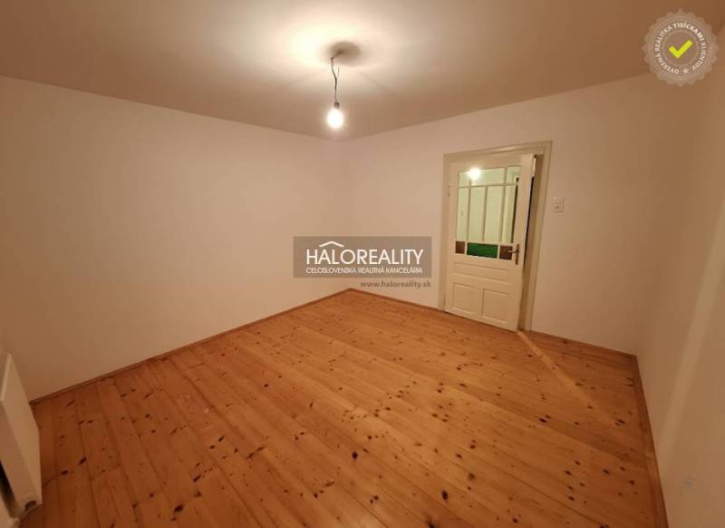 An empty room in a family house with a wooden decor floor and a simple light fixture.