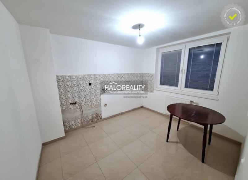 A room in a family house with white walls, a window, and tiles.