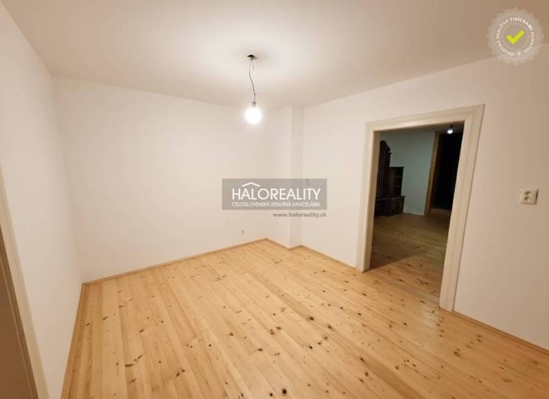 An empty room in a family house with a wood-patterned floor and simple lighting.