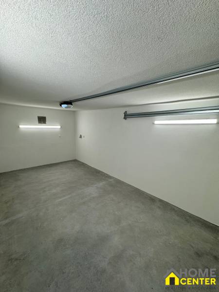 Interior of a garage with a concrete floor and lighting in the garage space.