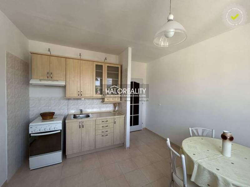 A kitchen in a studio apartment with a kitchenette, dining table, and bright interior.