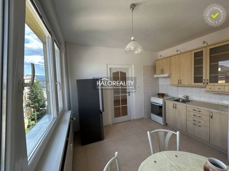 A bright kitchen in a studio apartment with modern cabinets and a view from the window.