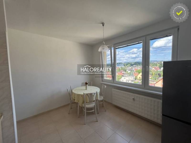 A kitchen in a studio apartment with a view of the city and seating at the table.