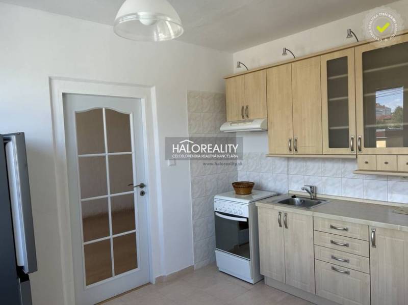 A kitchen with wooden decor, a tiled wall, a white stove, and white doors.