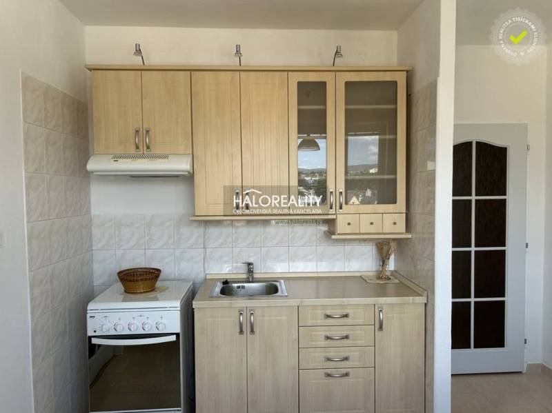 A kitchen in a studio apartment with a wooden decor and white tiles.