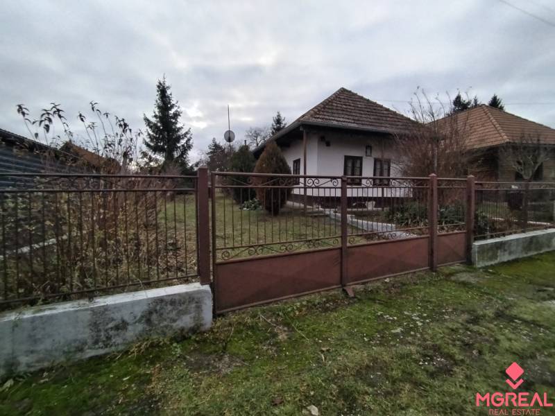 A family house in Dolný Pial surrounded by a garden and a fence, overcast weather.