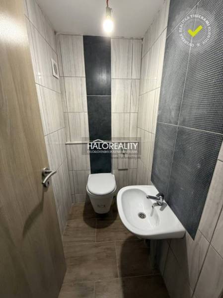 A toilet with a sink in a family house, tiled walls, floor with wooden decor.