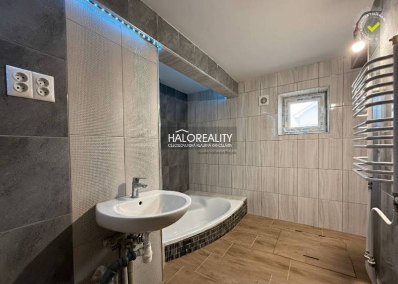 A family house bathroom with a bathtub, a sink, and a wooden decor floor.