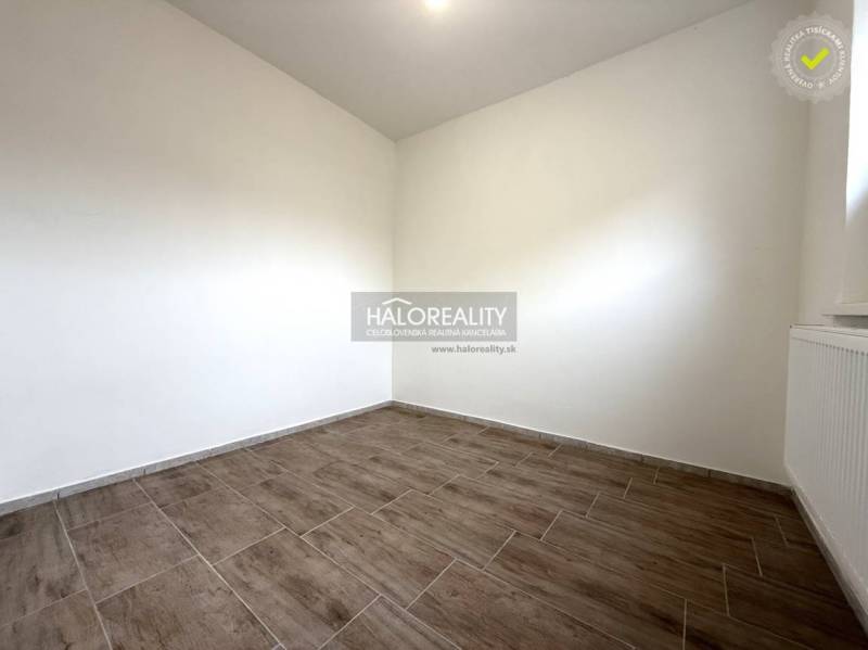 A room with a wooden decor floor in a family house, light walls, radiator.