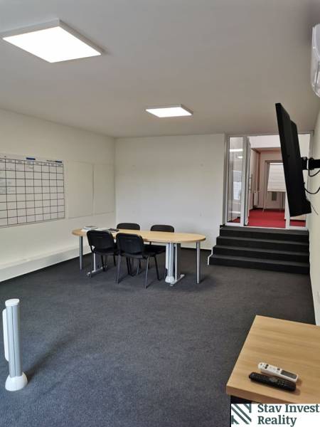 Offices with a conference table, chairs, a board, and a TV on the wall.