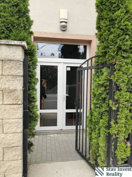 The entrance door on Šamorínska Street in Senec surrounded by greenery and a fence.