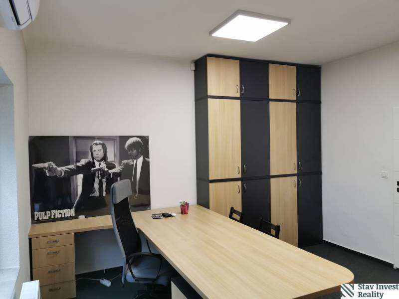 Office with a desk, cabinets, and a poster, floor with wood decor.