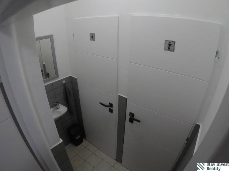 Toilets in offices, containing a sink, mirror, and doors with symbols.