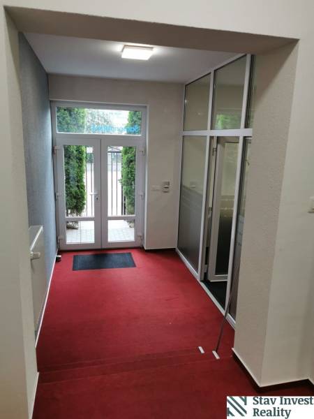 An office interior with a red carpet and glass doors to the outside space.