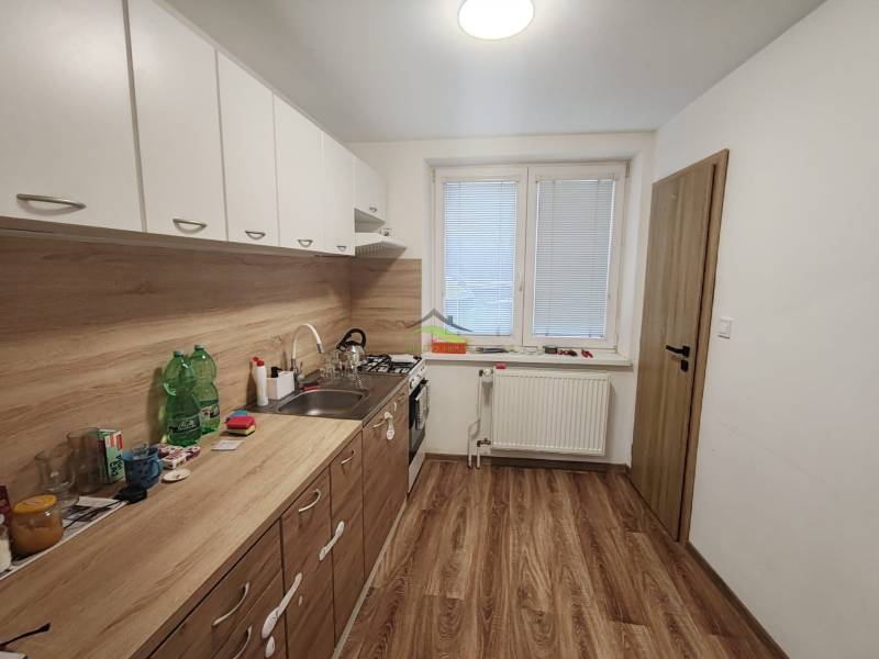 Kitchen in a 3-room apartment, floor with wood decor, white kitchen unit.