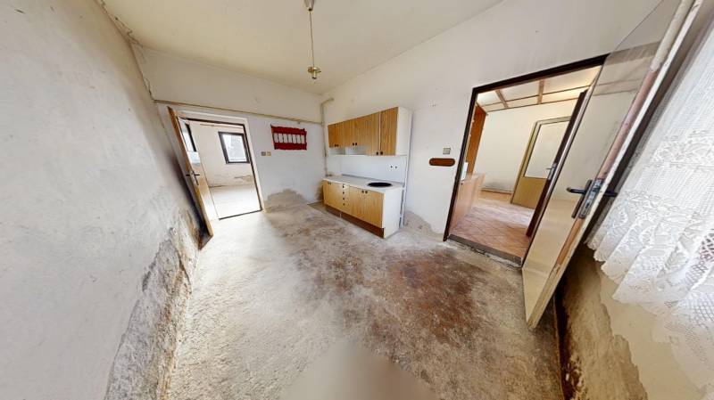 The interior of a family house with a simple kitchen unit and a worn-out floor.