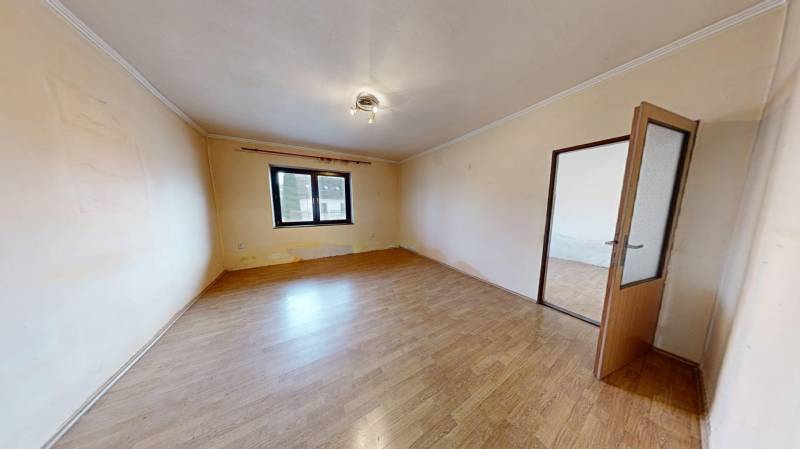 A room in a family house with a wooden decor floor and a large window.