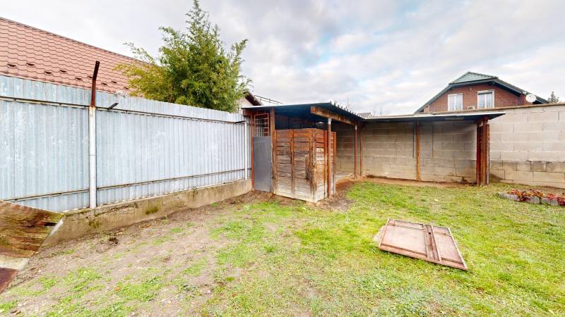 A garden at a family house on SNP Street in the village of Veľké Leváre with a metal fence.