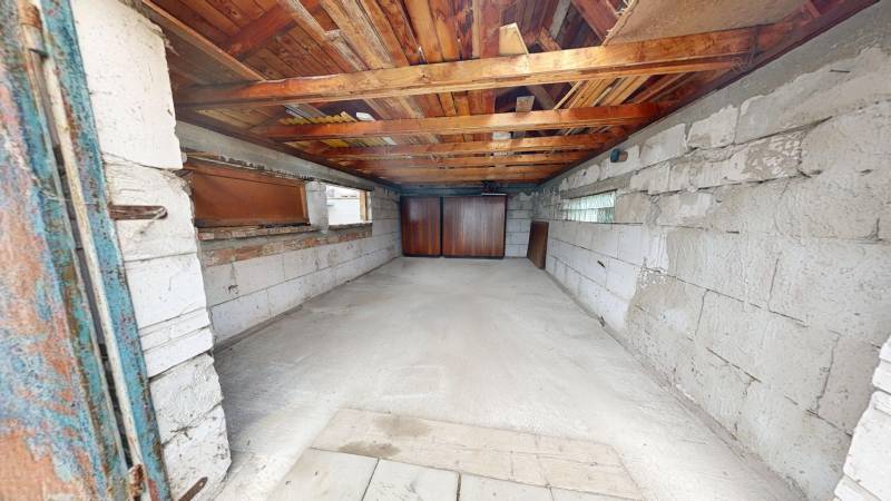 A garage of a family house with a concrete floor and a wooden ceiling.
