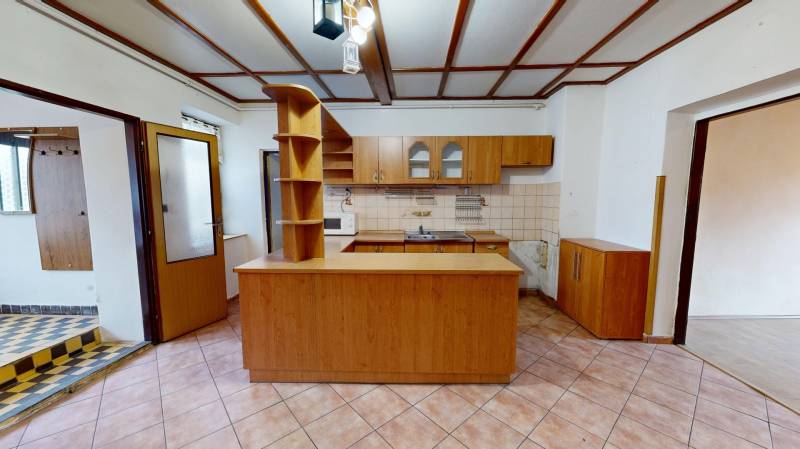 A kitchen in a family house with ceramic tiles and a wooden decor kitchen unit.