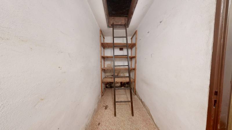 Narrow room with shelves and stairs to the attic in a family house.
