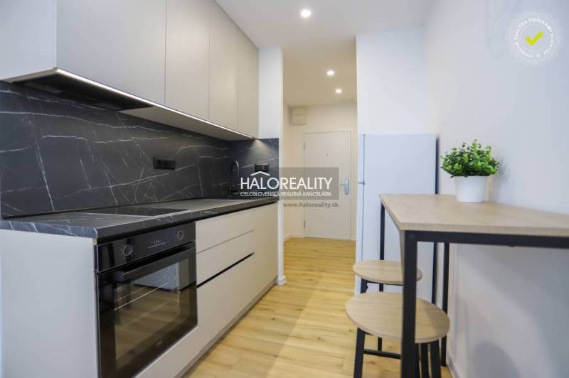 A kitchen unit with a marble design and a floor with a wood design in a studio apartment.