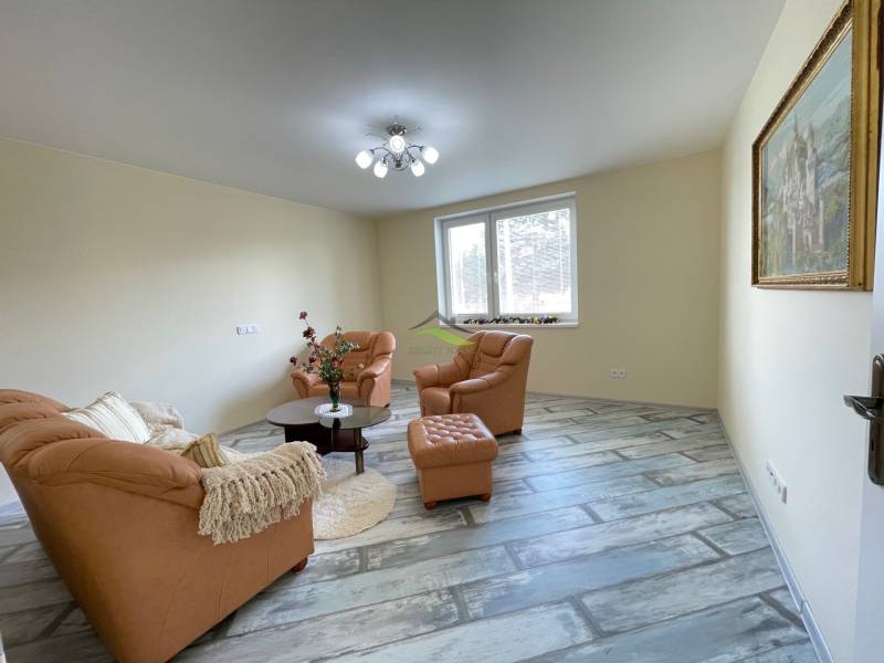 Living room with a brown sofa and wood-patterned flooring in a family house.