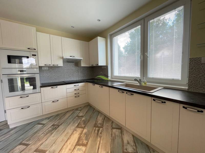 A kitchen in a family house with white cabinets and a wooden decor floor.