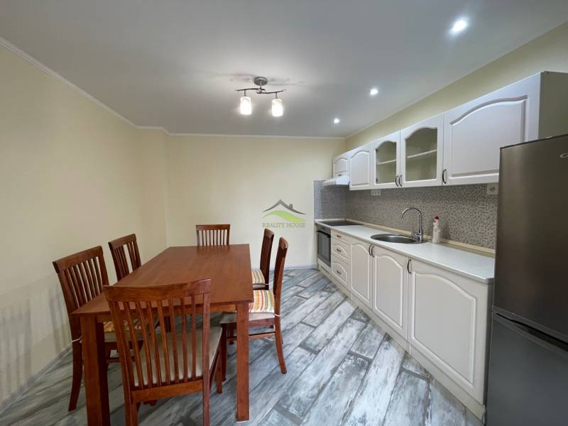 A kitchen in a family house with a wood-patterned floor and a dining table.