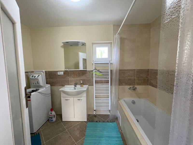 The bathroom in the family house includes a bathtub, a washing machine, a sink, and a tiled floor.