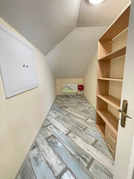 A narrow hallway with a shelving unit and a wooden decor floor in a family house.