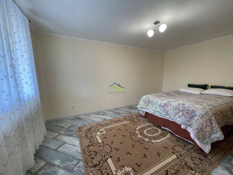 A bright bedroom in a family house with a bed and a patterned carpet.