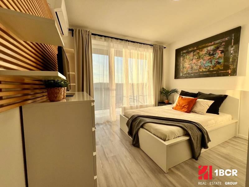 Bright bedroom with a bed and decorative pillows, wooden decor flooring, studio apartment.