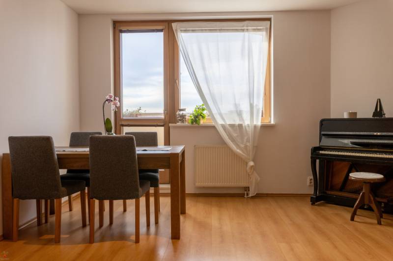 Dining area in a 3-room apartment with a piano and a wooden decor floor.