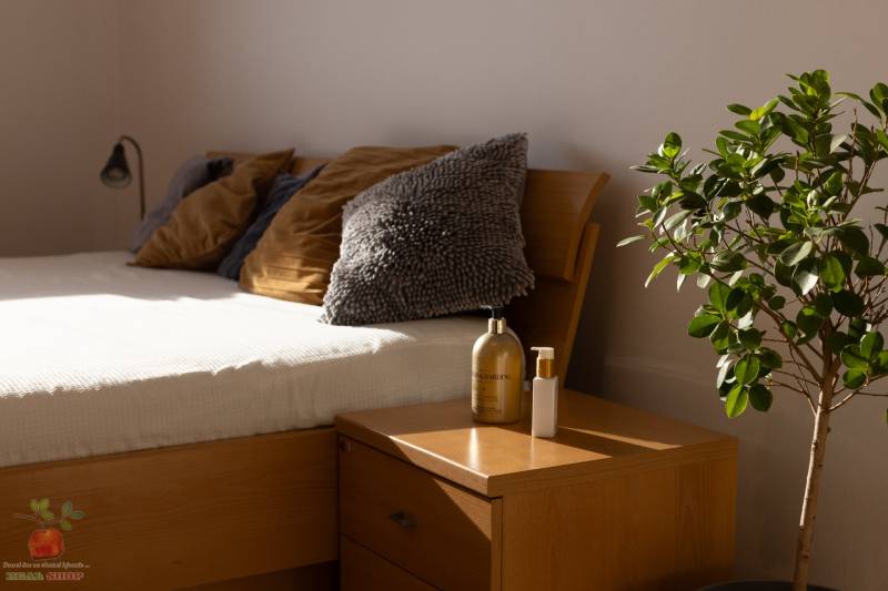 Bright bedroom in a 3-room apartment with a wooden bed, nightstand, and a plant.