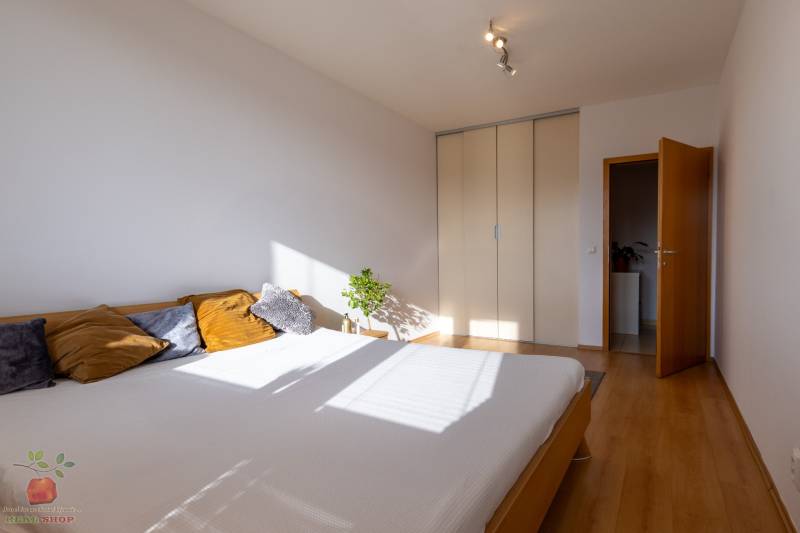 A bright bedroom with a bed, built-in wardrobe, and wooden decor flooring in a 3-room apartment.