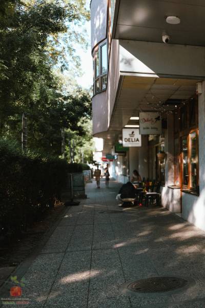 Sidewalk on Záhradnícka Street in Bratislava with shops and people.