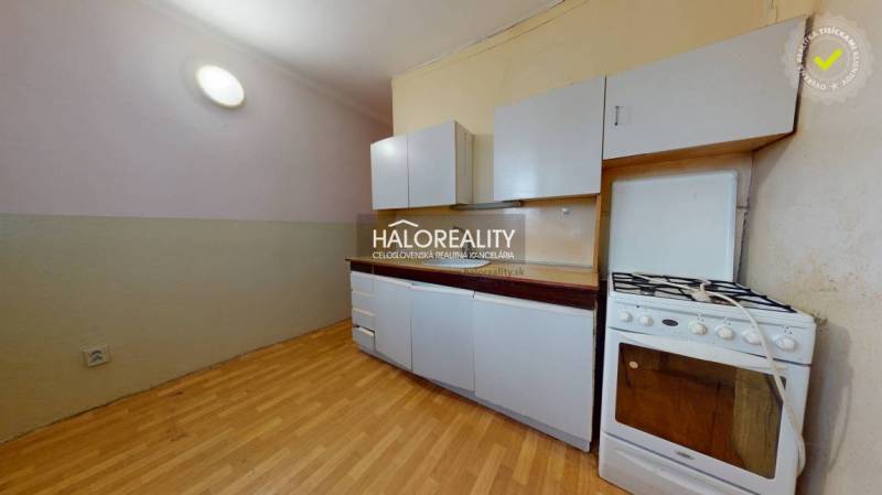A kitchen in a 3-room apartment with a white kitchen unit and a floor with a wood design.