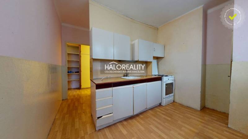 A kitchen in a 3-room apartment with a wooden decor floor and white cabinets.