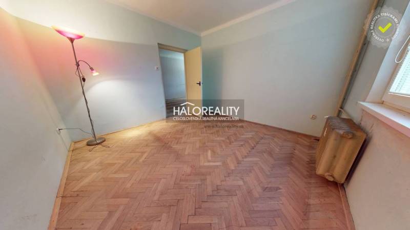 A room with a lamp, radiator, and wooden decor flooring in a three-room apartment.