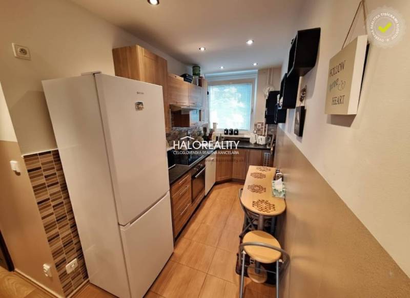 A kitchen in a 3-room apartment with a wooden decor floor and a dining area.