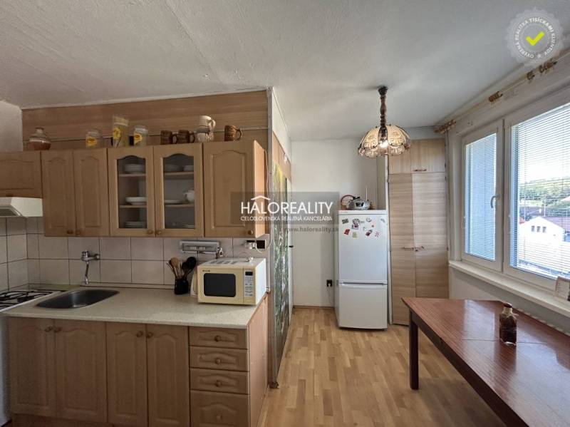 A kitchen in a 2-room apartment with a wood-patterned floor, light cabinets, and a table.