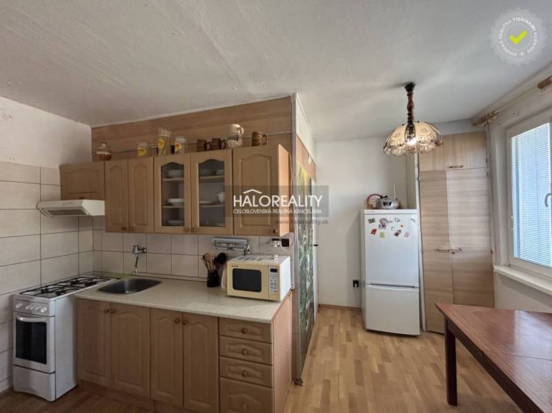 A kitchen in a 2-room apartment with a kitchen unit, refrigerator, and floor with a wooden decor.