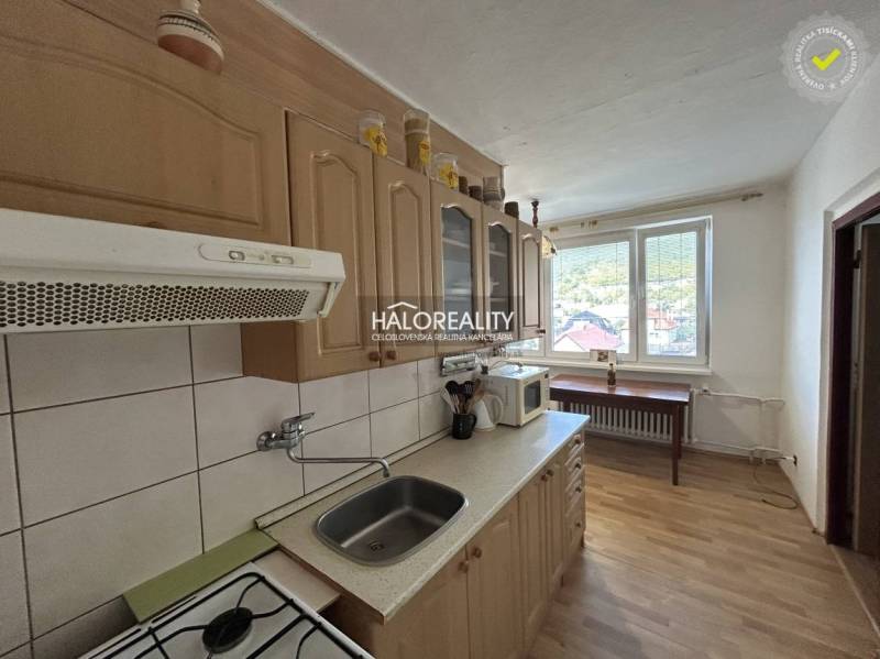 A kitchen in a 2-room apartment with a wooden decor floor and a view from the window.